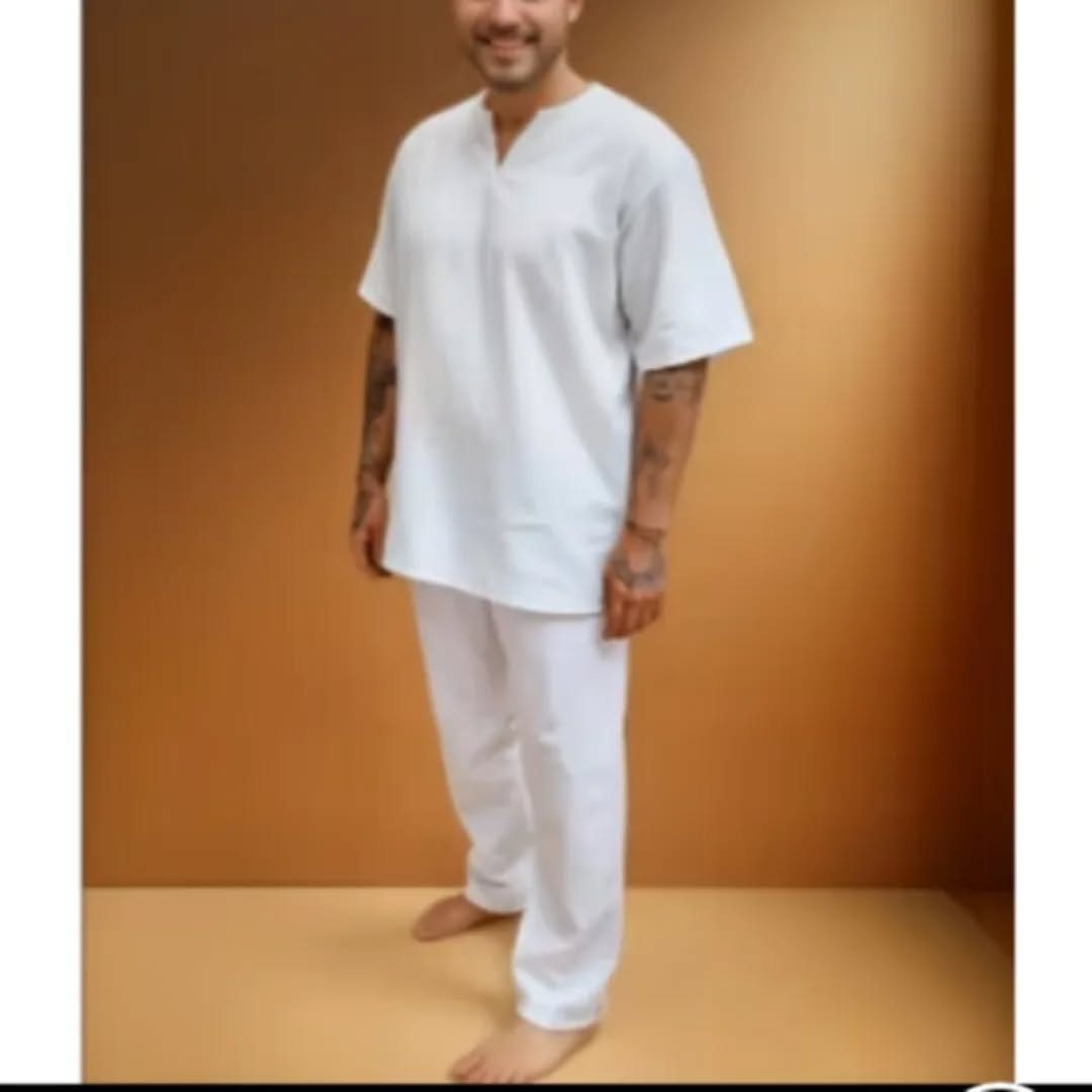 Homem de pé descalço com conjunto branco de axé, sorrindo